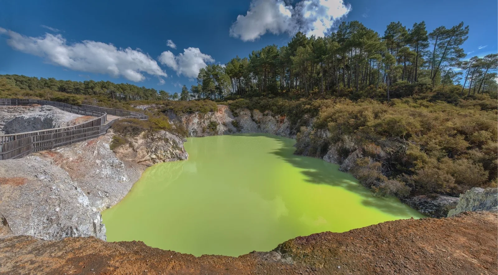 Devil's Bath at Wai-O-Tapu, a bright lime-green crater lake with a boardwalk running along its rim