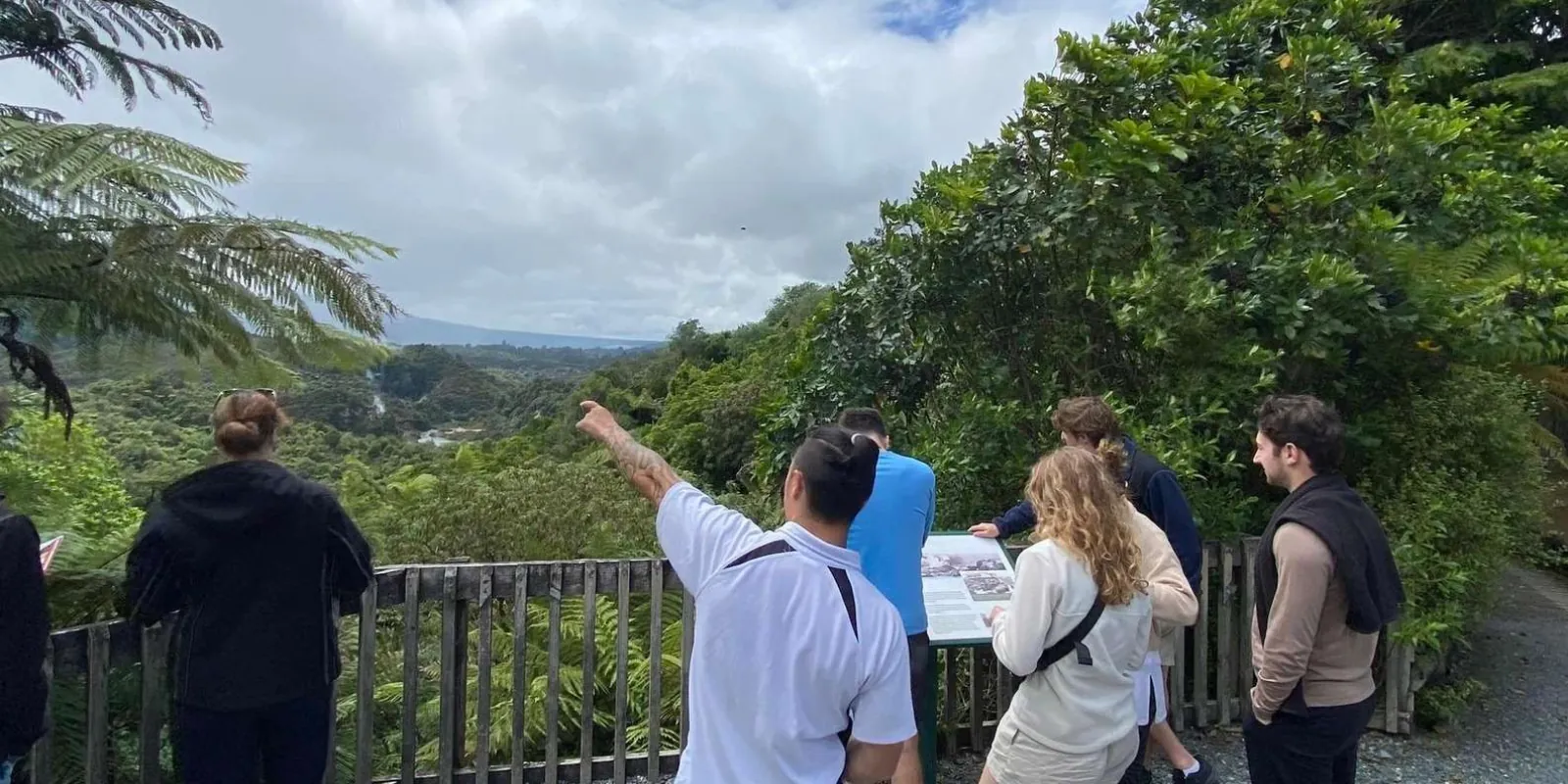A guide pointing out features to a small tour group at a Waimangu Volcanic Valley lookout