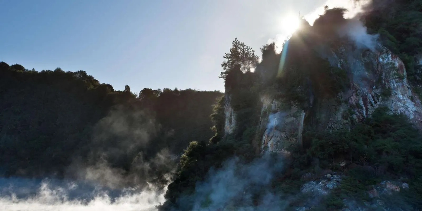 Backlit steam rising along the cliff face of the Waimangu Volcanic Valley