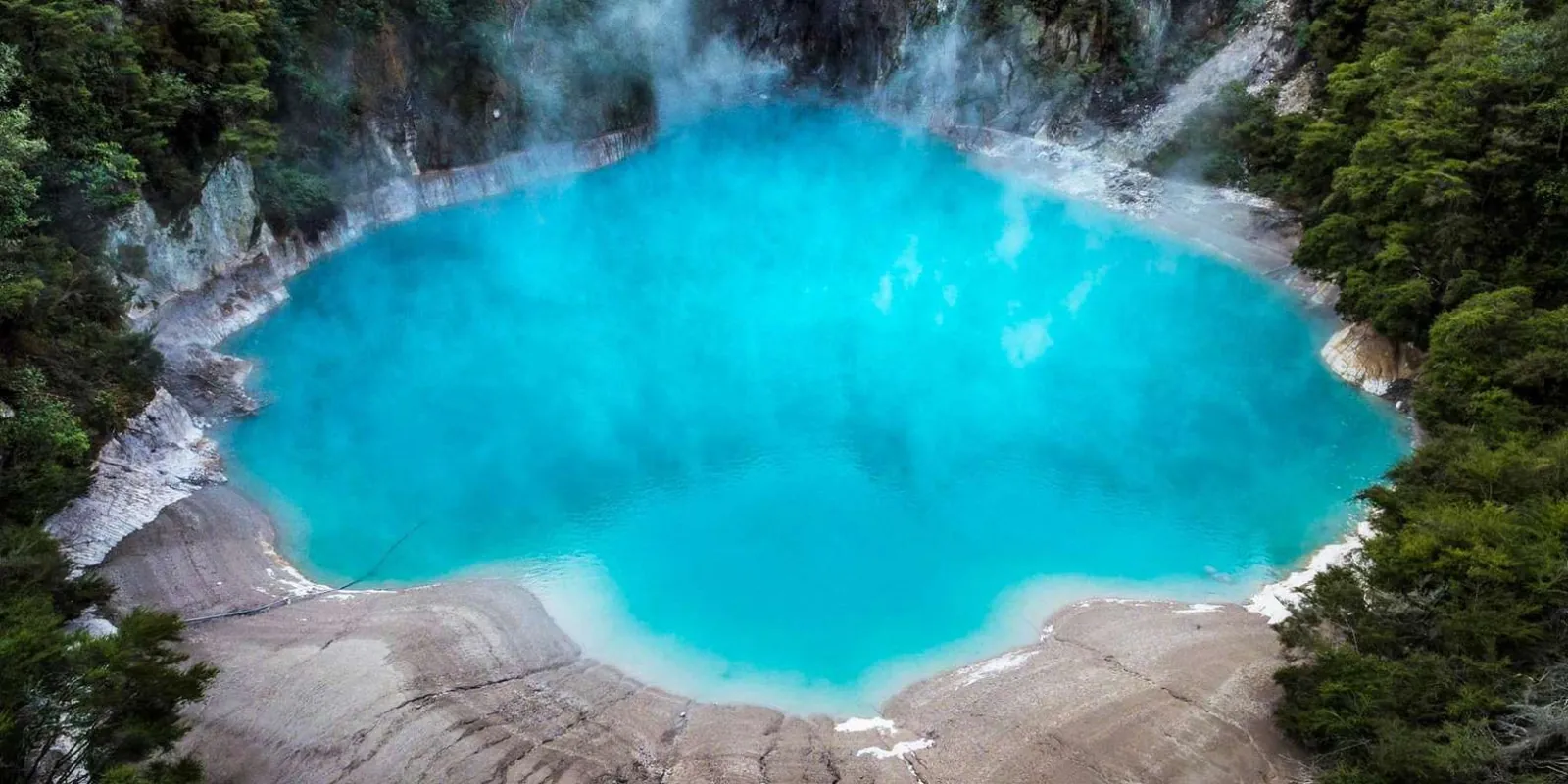 Inferno Crater Lake at Waimangu, an intense turquoise basin ringed by native bush